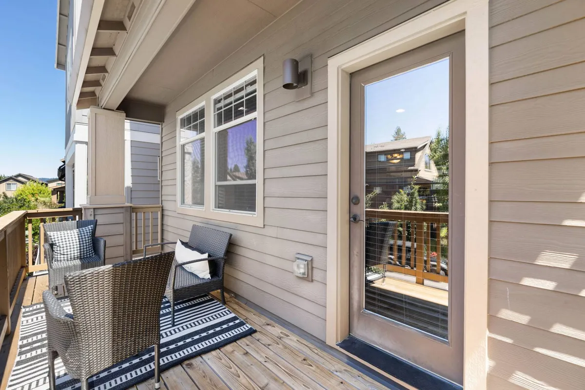 This exterior shot features an outdoor seating area adjacent to a doorway, complete with a decorative rug and cozy furnishings. The area is ideal for relaxing, enjoying morning coffee, or informal gatherings after a productive day.