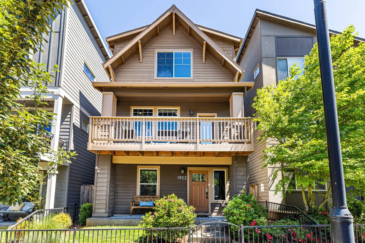 A welcoming front porch surrounded by greenery, featuring a wooden railing and double-story windows. The area exudes a cheerful and inviting atmosphere, making it ideal for morning coffee or an evening gathering. The porch is gated and secure, making it suitable for supervised pet time.