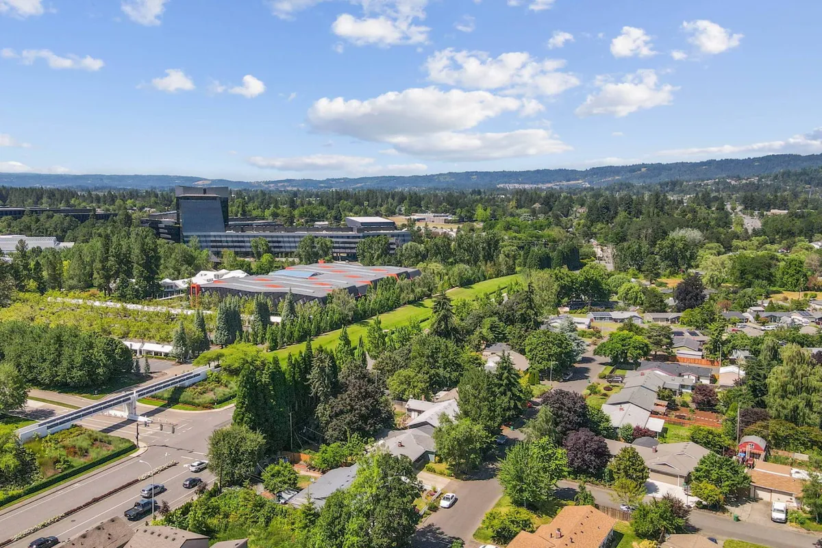 This wide view highlights the surrounding neighborhood, with green parks, residential areas, commercial buildings, and accessible roadways. The image evokes a sense of community and ease of movement within the area.