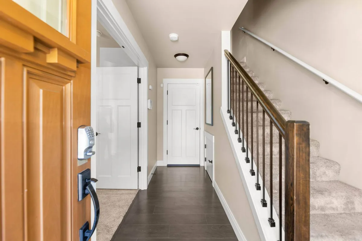 A view of the home's front door, staircase, and hallway, offering a sense of transition from the exterior to the interior. The space is inviting and gives an immediate sense of arrival, with natural light and a welcoming layout.