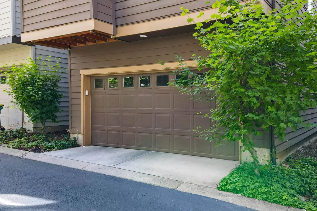 An inviting exterior shot featuring the house’s modern facade, well-maintained landscaping, and a prominent garage door. The image captures the welcoming atmosphere as one approaches the property, with greenery and an open, community-oriented vibe.